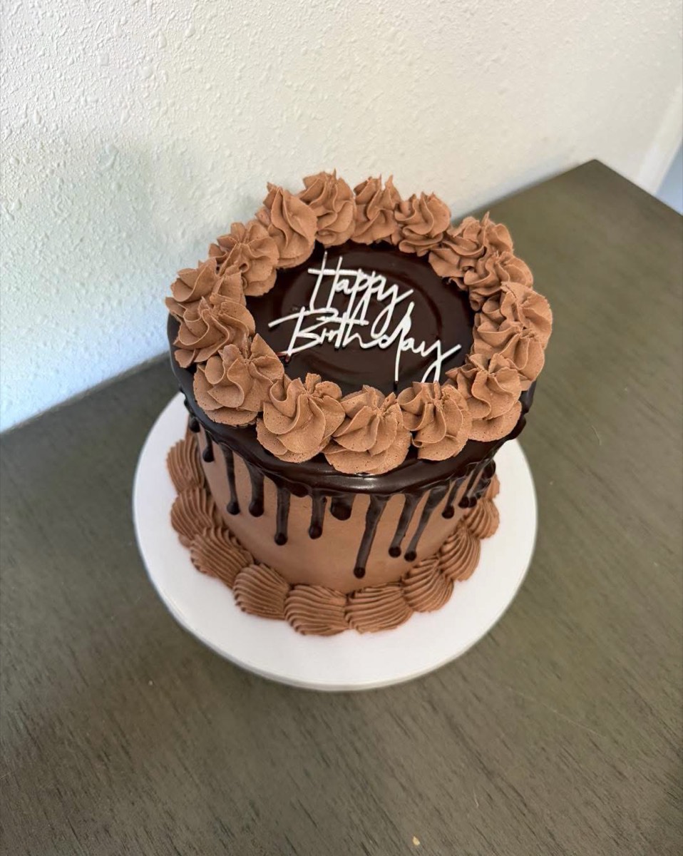 A chocolate buttercream cake with a ganache drip, piped rosettes and a Happy Birthday topper