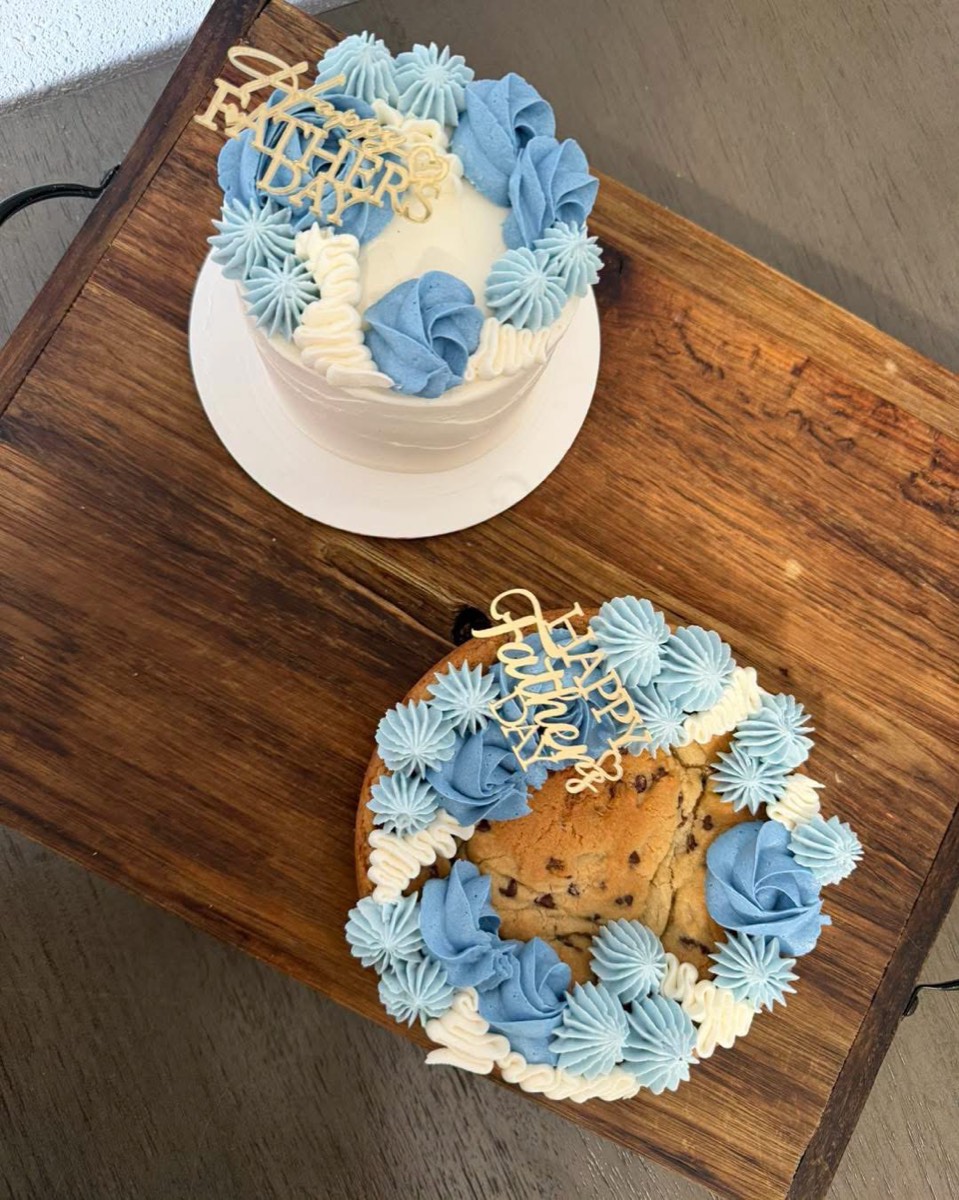 A blue and white piped cake beside a matching decorated chocolate chip cookie cake
