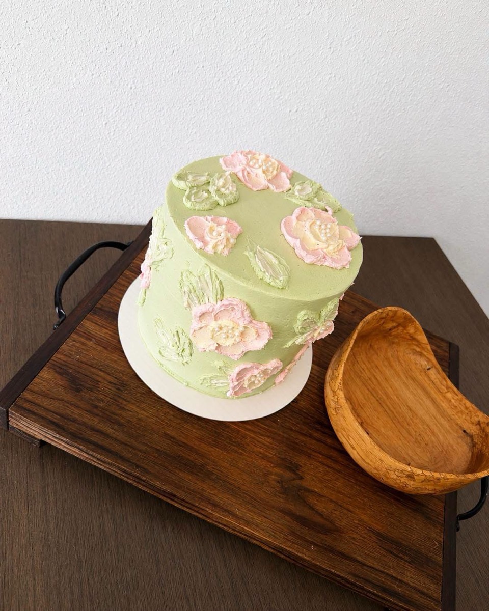A sage green cake with pink and cream palette-knife buttercream flowers