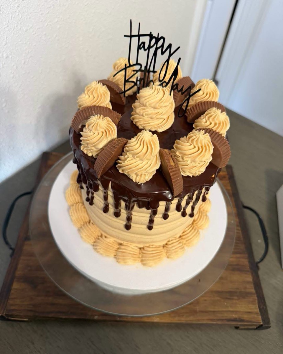 A cake with peanut butter buttercream swirls, chocolate ganache drip and peanut butter cups