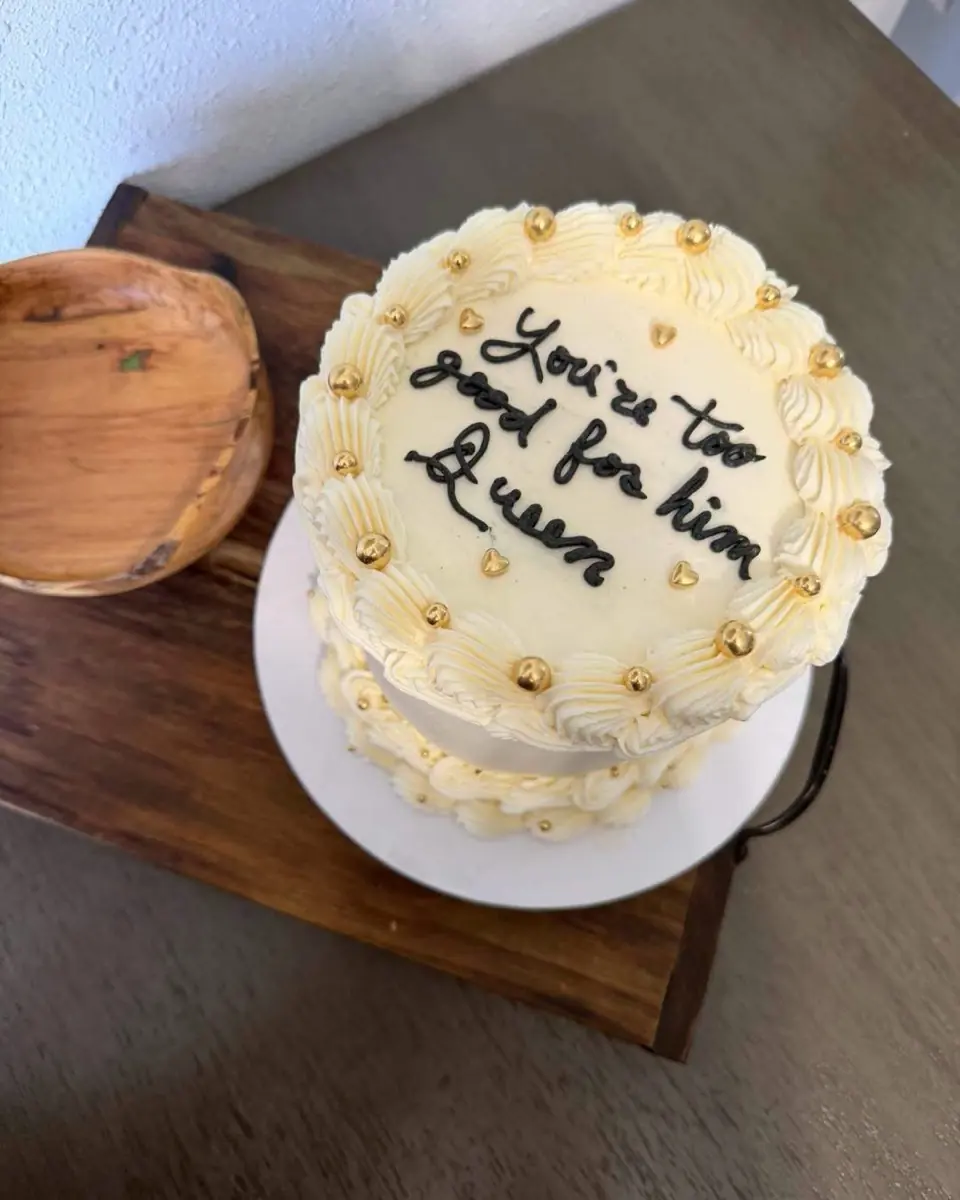 A vintage-piped buttercream cake topped with gold pearls and handwritten black lettering