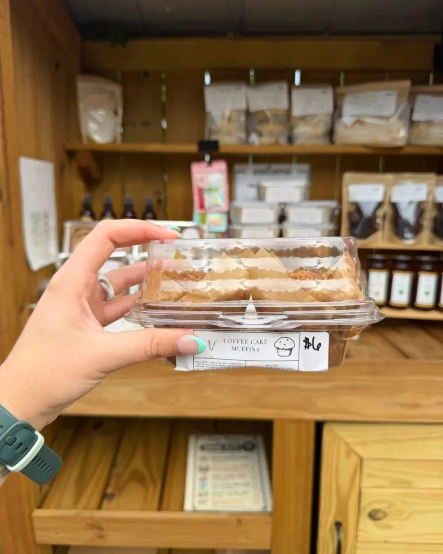 A boxed set of coffee cake muffins held up in front of the stand shelves