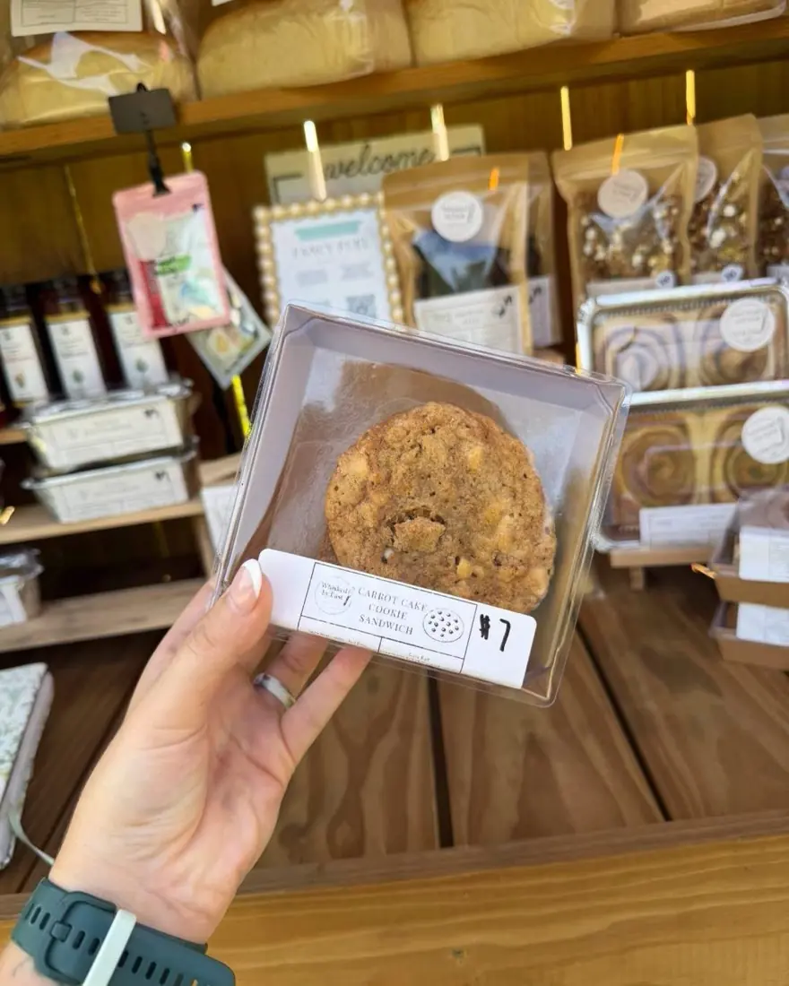 A carrot cake cookie sandwich in a clear box, held up at the stand