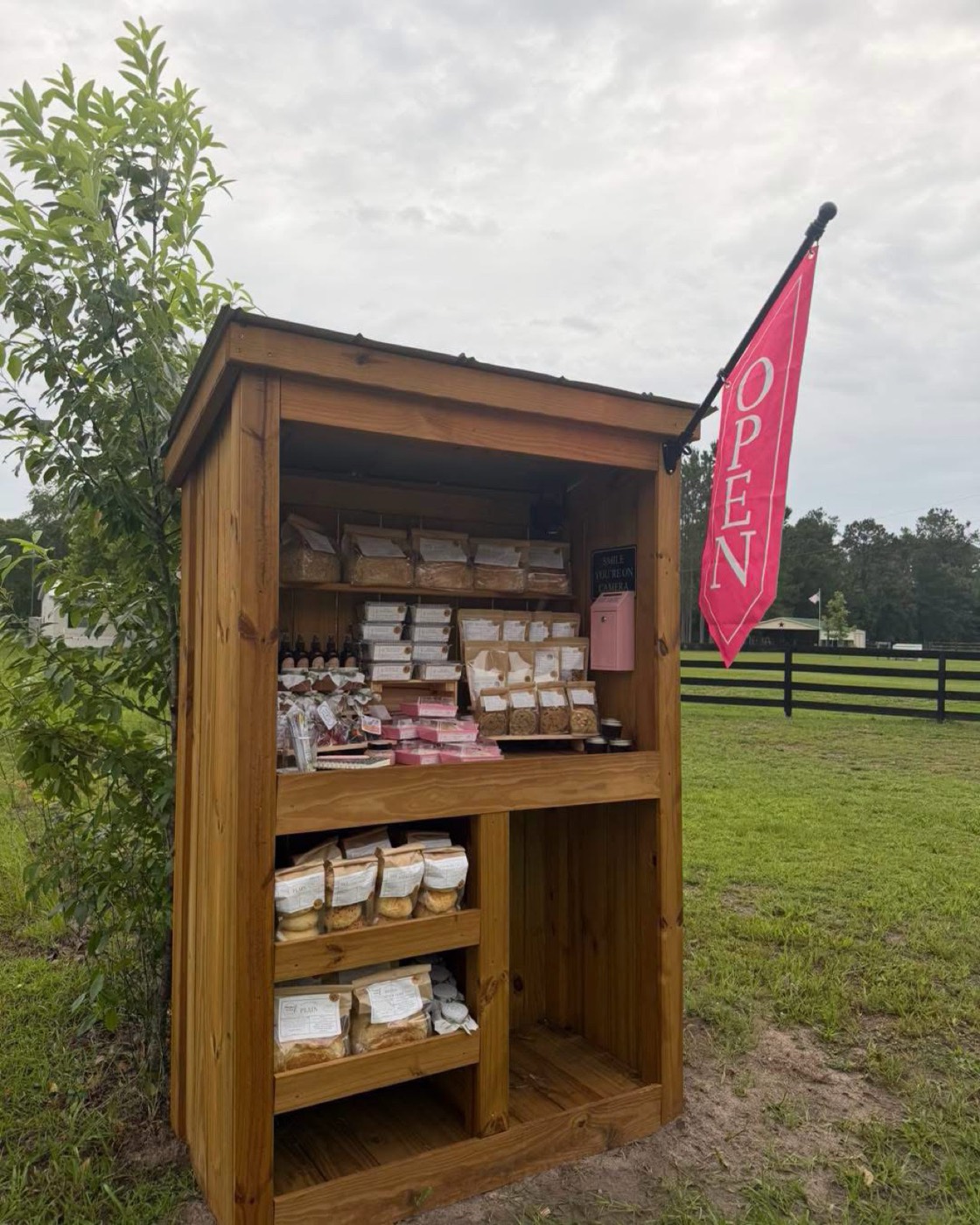 The Whisked by East farm stand beside a pasture, with a red OPEN flag flying