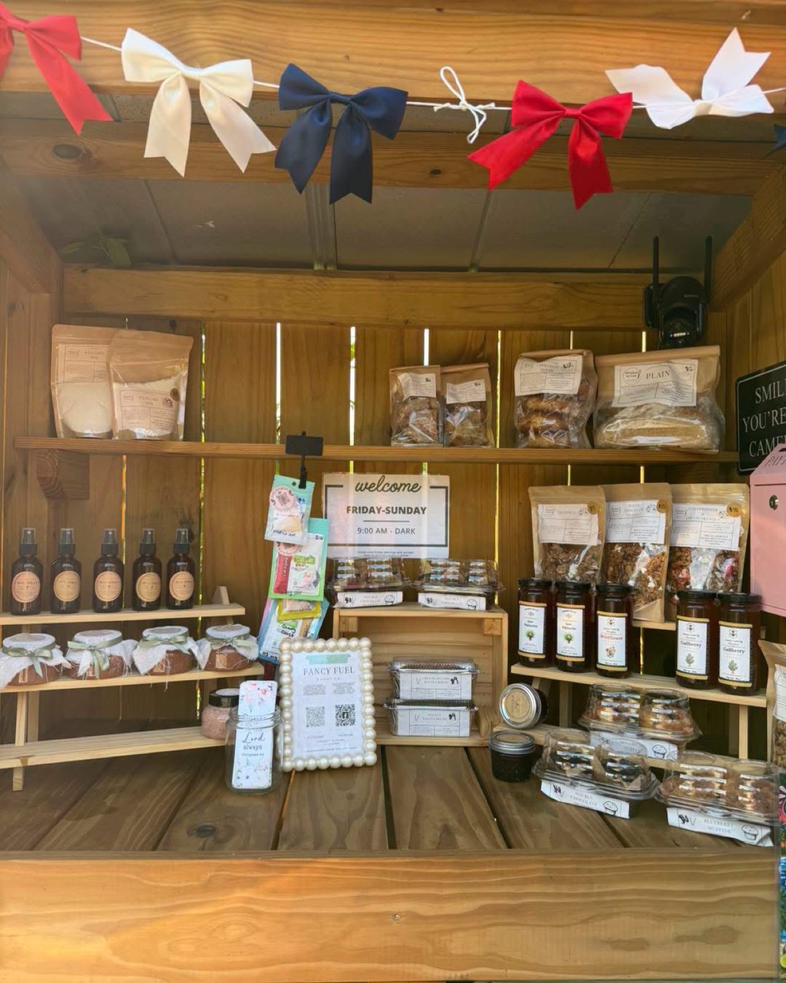 Inside the stand: shelves of bagged sourdough, granola, honey and muffins under a welcome sign