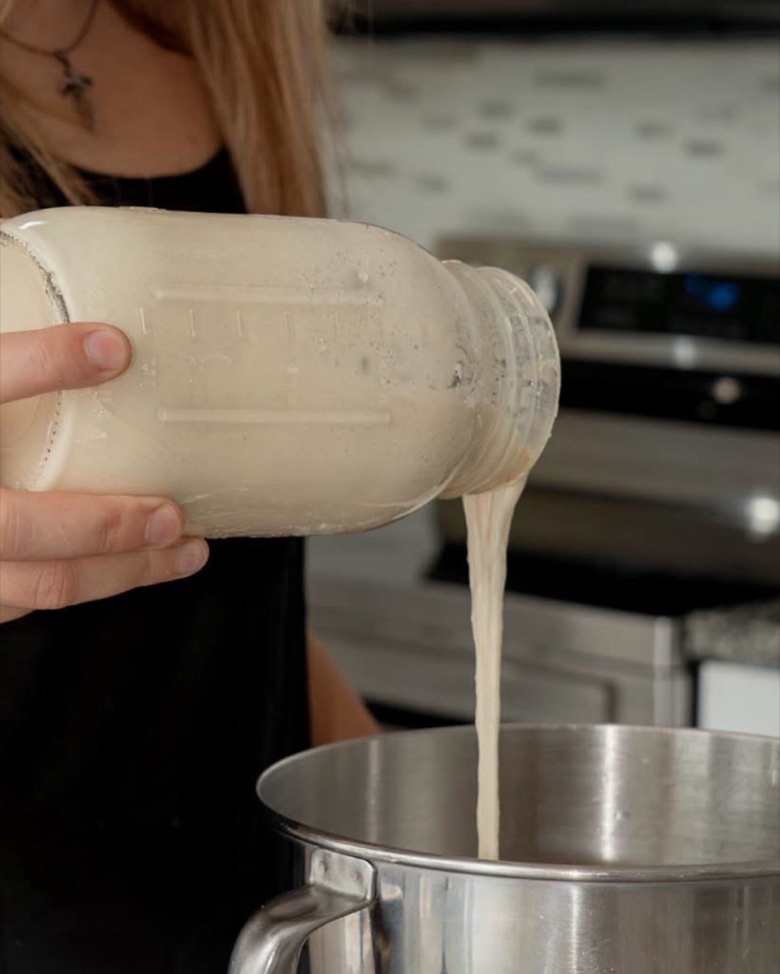 Sourdough starter being poured from a mason jar into a mixing bowl